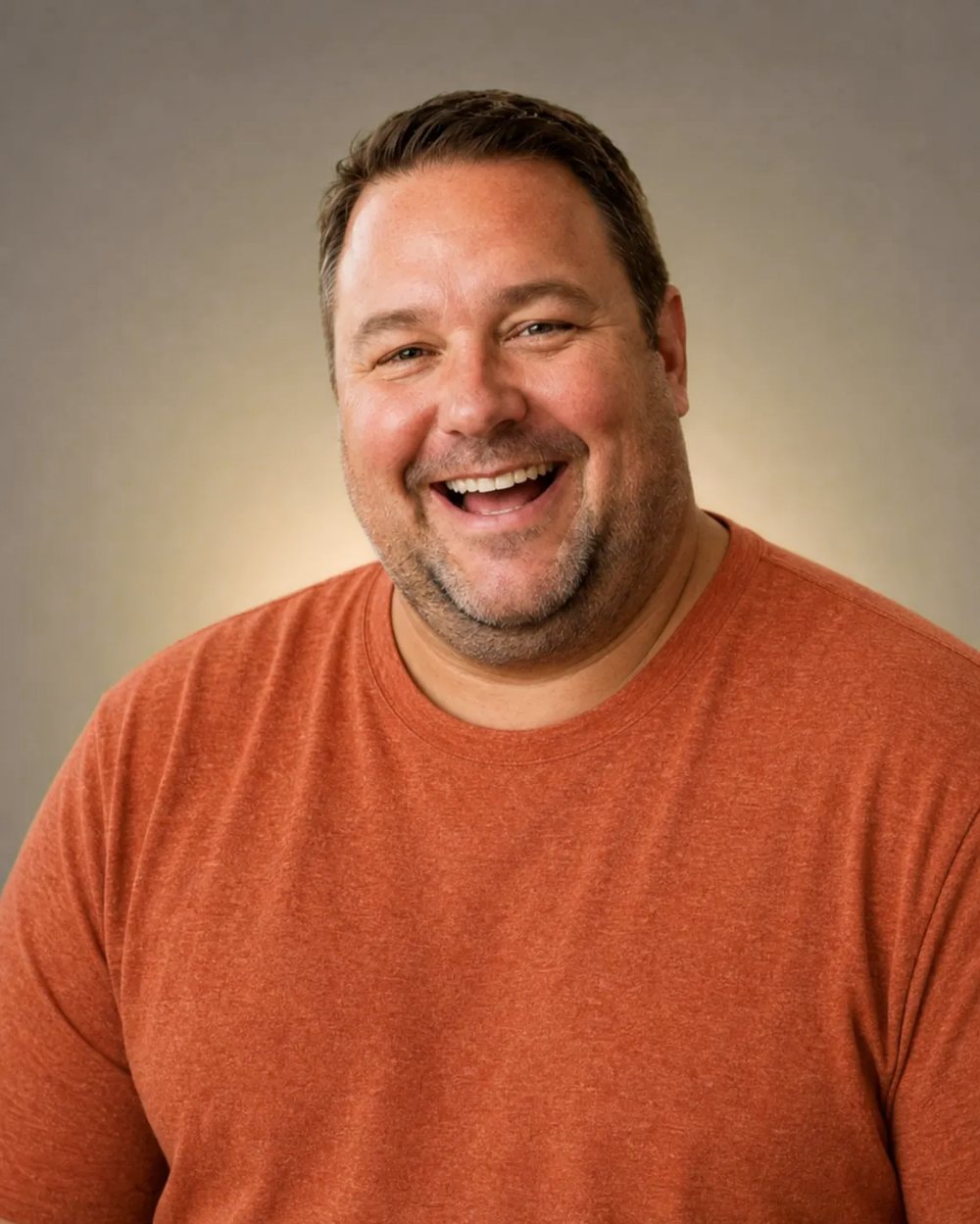 Man laughing in a rust-coloured tee